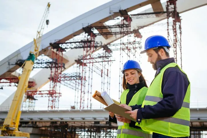 Construction Workers Looking At Plans to Build Bridge