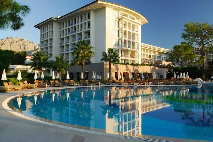 Hotel pool with palm trees and hotel in background.