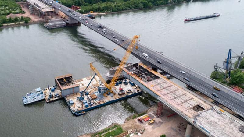 Picture of crane on water constructing bridge highway.
