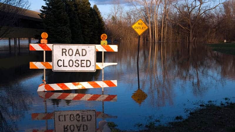Road closed sign in front of flooded road.
