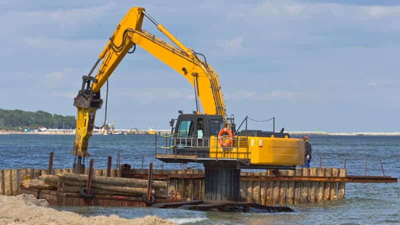 Construction equipment installing pier in water.