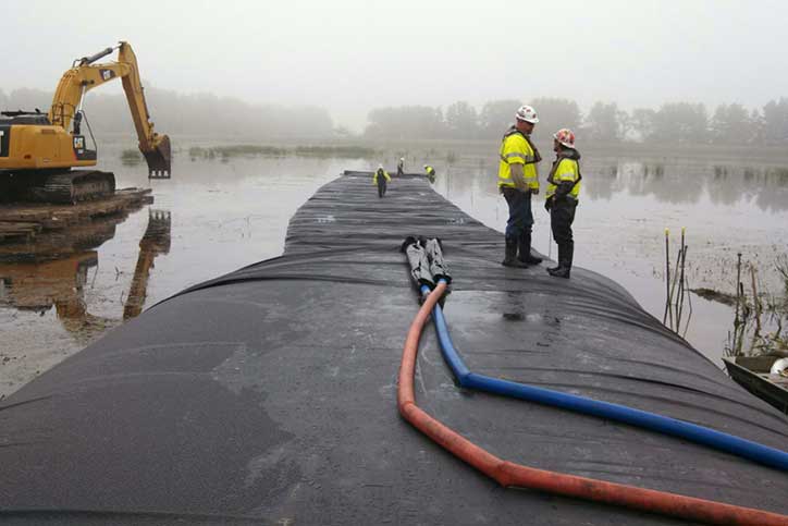 Two workers standing on inflated cofferdam from Dam-It-Dams.