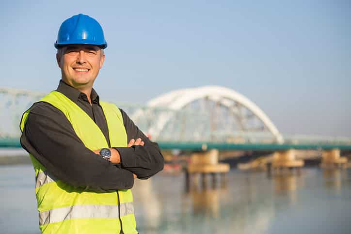 Engineer, architect or supervisor on a construction site of a new bridge. About 45 years old, Caucasian mature adult man smiling about inflatable cofferdams not being expensive.
