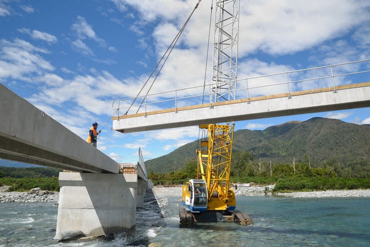 Builders construct a concrete bridge over a small river