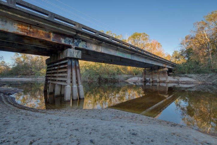 Low angle of an old bridge over an almost dry river in rural Mississippi.